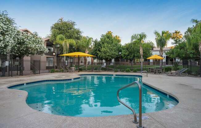 A swimming pool surrounded by trees and umbrellas at Sterling Point Apartment Homes, Phoenix, AZ