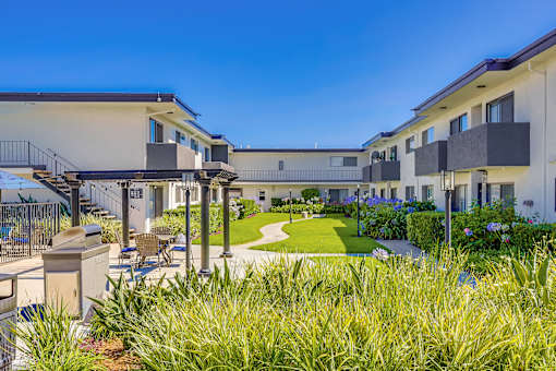 A sunny day at a modern apartment complex with a well-maintained lawn and landscaping.