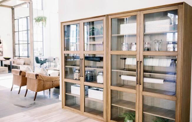 Resident lounge area with wooden and glass book cases with decorative items displayed at The Merchant Apartments, South Carolina 29403