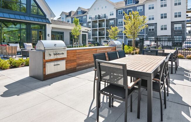a patio with a barbecue grill and a table and chairs