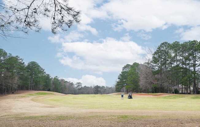 A golf course with two golf carts on the green.