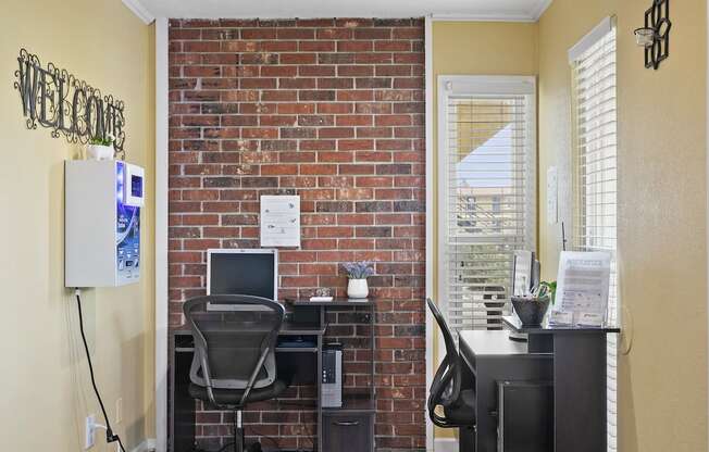 an office with a brick wall and a desk with a computer