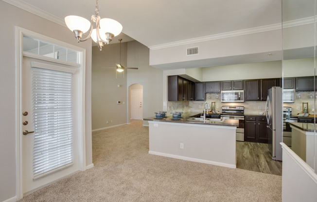 View of Kitchen with Hanging Lights, Plank Wood Flooring, and View of Living Room at Raveneaux Apartments