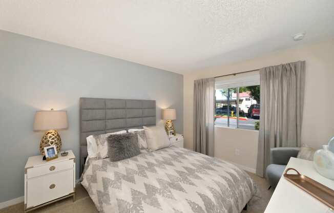 Bedroom with Mattress with Gray/White Comforter, Carpet, White Bedside Dresser with Lamp and Windows