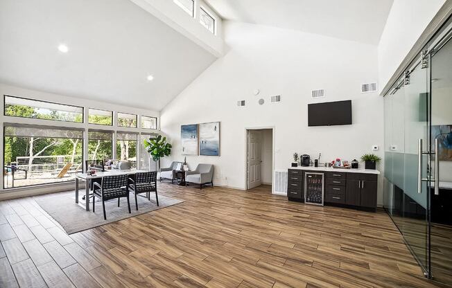 the living room and dining area of a house with large windows and a wooden floor