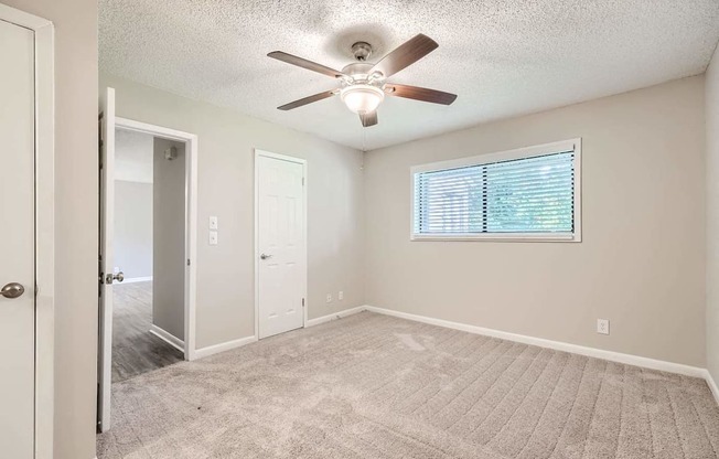 A room with a ceiling fan and a window with blinds.