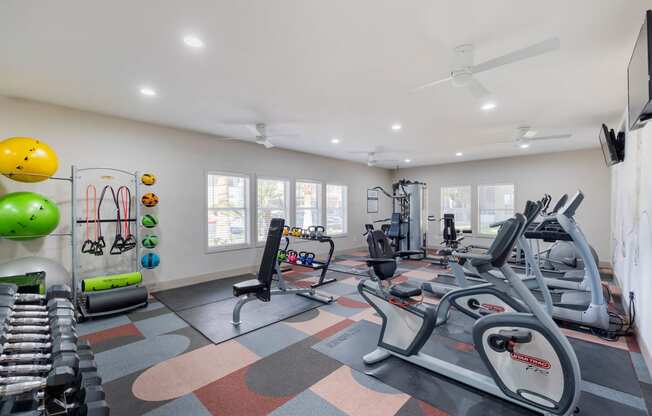 a gym with treadmills and other exercise equipment and windows at Paisley and Pointe Apartments, Las Vegas, 89130