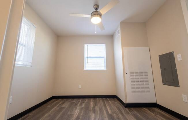 an empty living room with a ceiling fan and a door