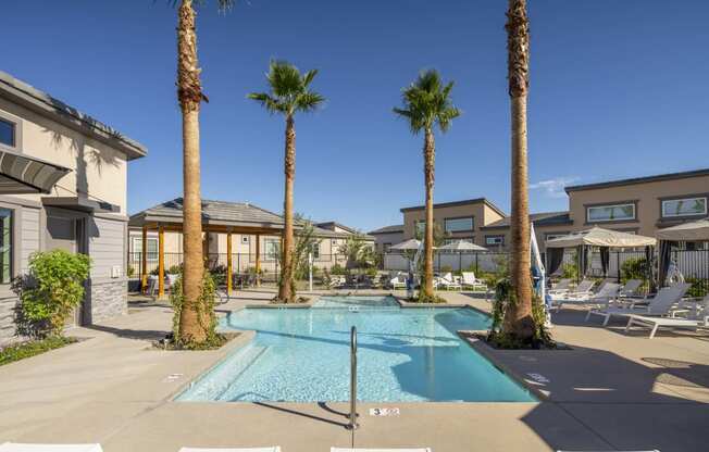 a swimming pool with palm trees in front of a building at Grandstone at Sunrise, Peoria, AZ
