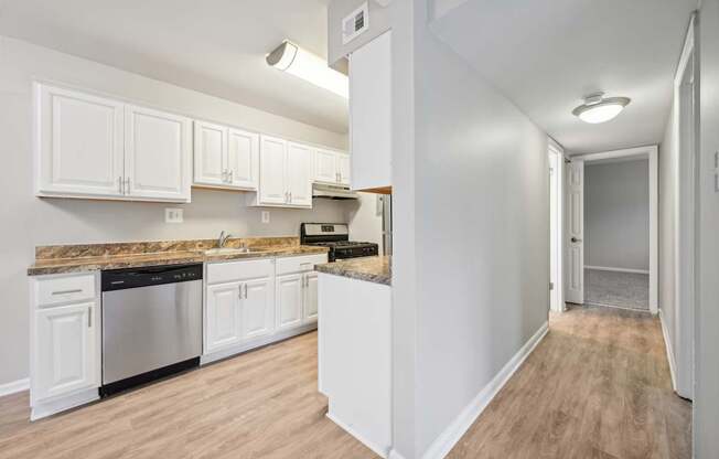 a kitchen with white cabinets and a counter top and looking into a hallway at ReNew Odenton