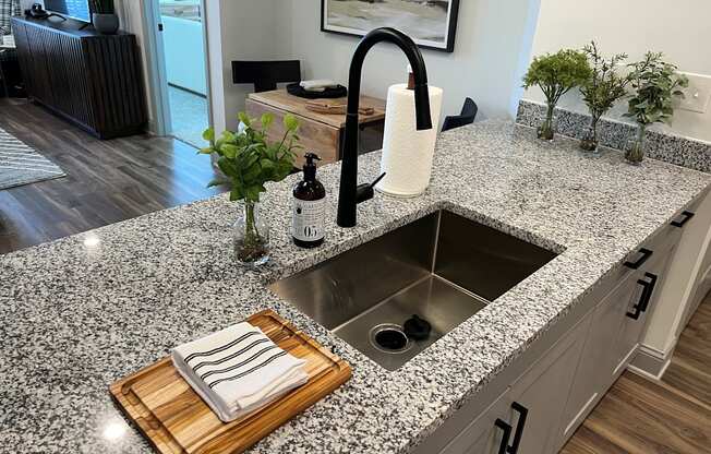 a kitchen sink with a wooden cutting board with a towel on it