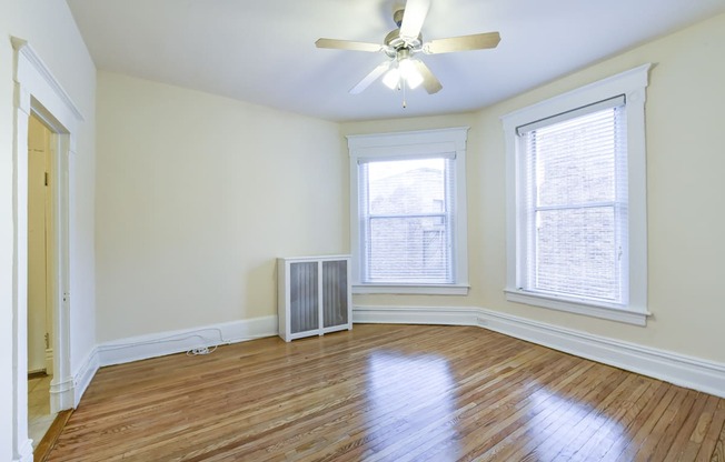 vacant living area with hardwood floors, large windows and ceiling fan at dupont apartments in washington dc