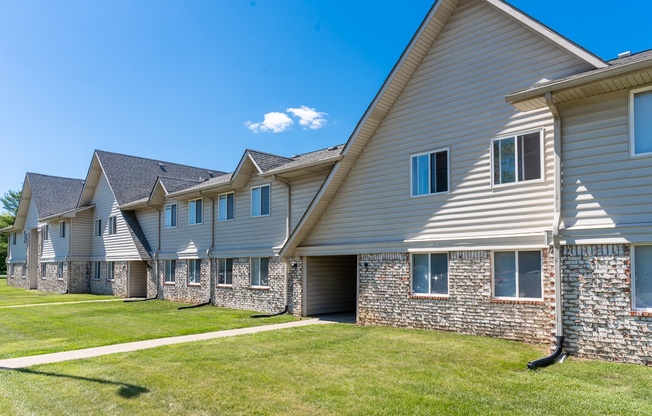 a row of houses with grey siding and a green yard