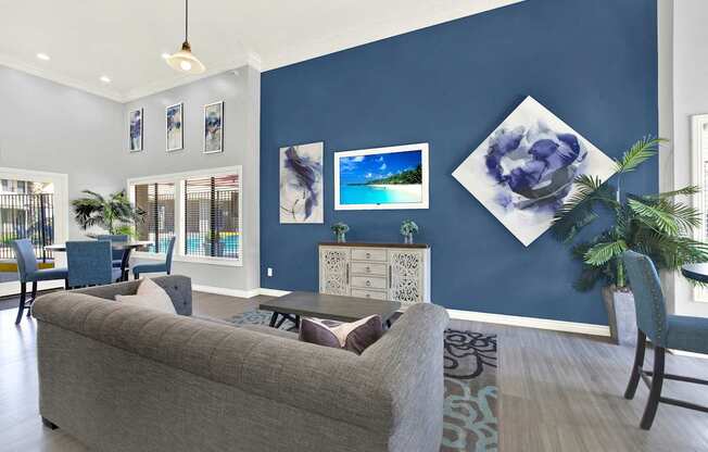 A living room with a grey couch and a blue wall.