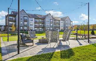 a patio with chairs and a table in front of an apartment building