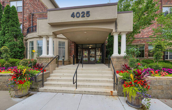 the front of a building with stairs and a entrance with flowers