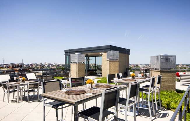 a rooftop terrace with tables and chairs and a view of the city