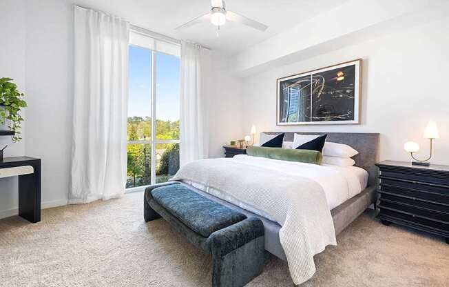 A bedroom with a large bed and a view of the outdoors through the window.