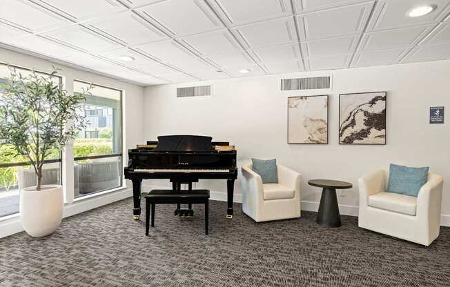 A room with a piano, two chairs, and a table.