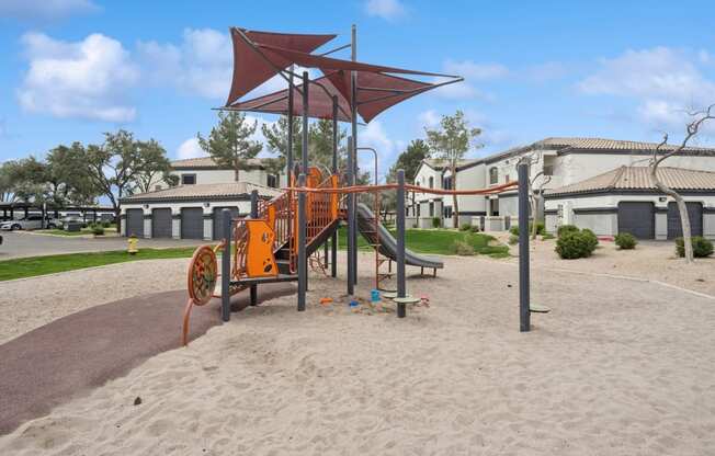 a playground with an orange swing set in front of a building