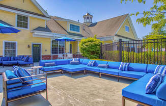 Outdoor patio with blue couches and umbrellas at Windsor Ridge at Westborough, Westborough, MA