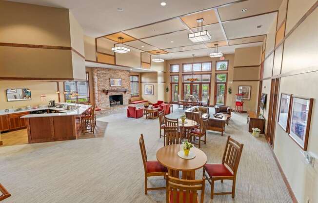 A large room with tables and chairs and a fireplace.