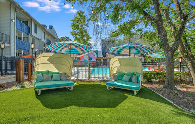 two lounge chairs with umbrellas in front of a pool