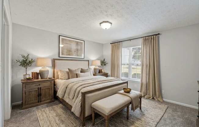 A bedroom with a large bed, a bench, and a side table with a plant.