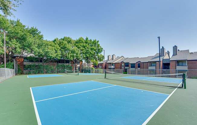 two tennis courts with apartments in the background