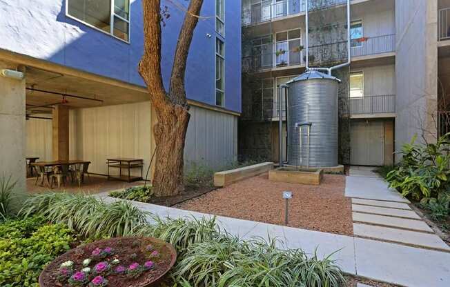 a courtyard with a tree and a large glass building