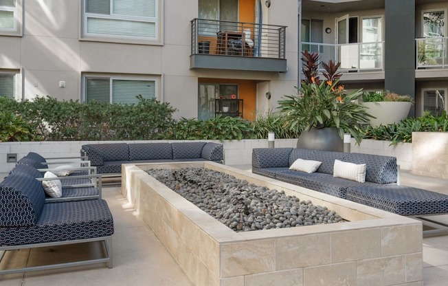 A patio with a couch, chairs, and a fire pit.