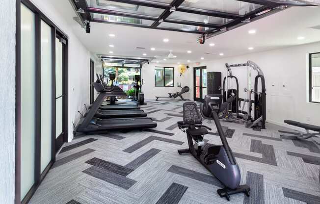 a workout room with treadmills and other exercise equipment