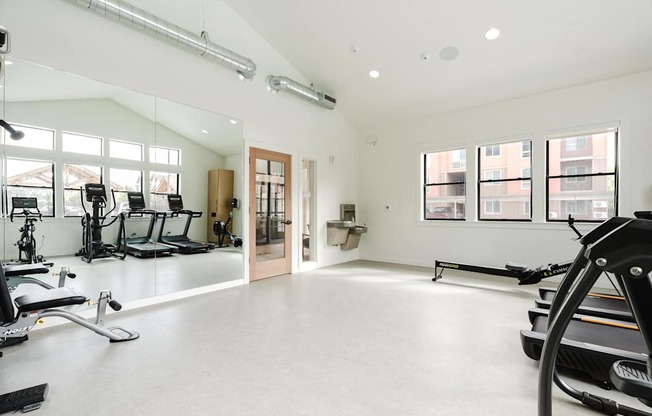 A spacious gym with a treadmill, elliptical machines, and other exercise equipment.