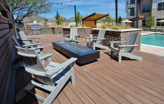 a group of chairs on a deck next to a pool at Hunters Creek Apartments, Denton