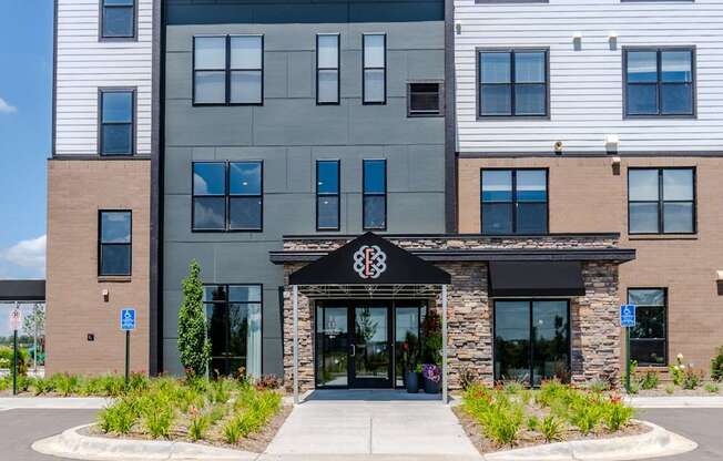 A modern building with a black entrance sign and a stone pillar.