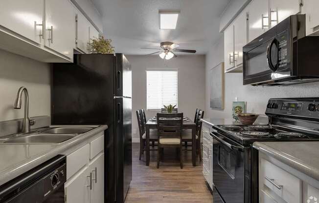 A kitchen with black appliances and white cabinets.