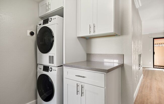 A white washing machine and dryer stacked on top of each other in a laundry room.
