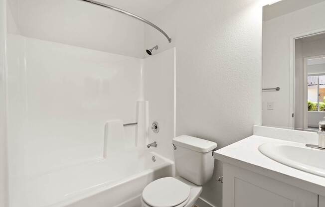 A white bathroom with a toilet, sink, and bathtub.