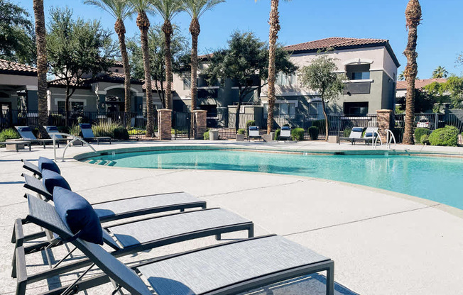 A poolside area with sun loungers and palm trees.