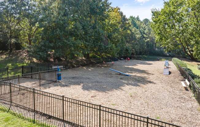 the playground is surrounded by a fence and trees at View at Lake Lynn, Raleigh, 27613