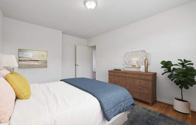 A bedroom with a bed, dresser, and plant.