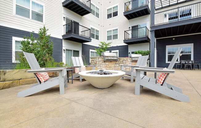 A patio with a fire pit and chairs.