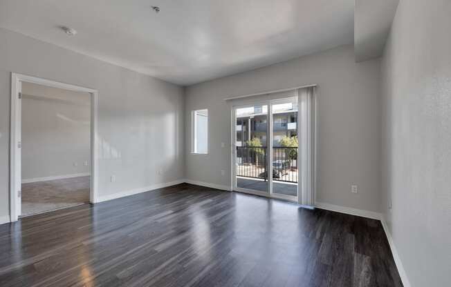 the living room of an empty apartment with wood flooring and glass doors