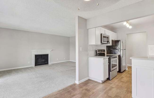 an empty living room with a kitchen and a fireplace at Summerwood Apartments, California