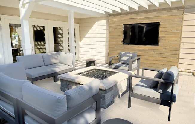 A patio with white furniture and a flat screen TV mounted on a wooden wall.