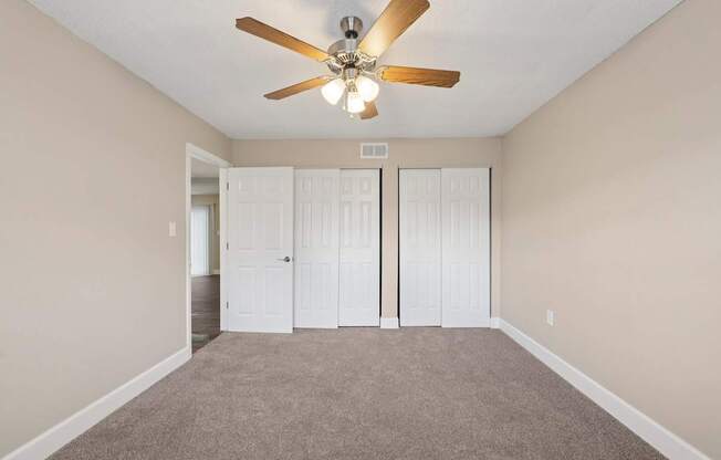 A room with a ceiling fan and carpeted floor.