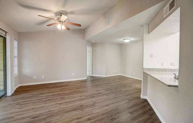 an empty living room with a ceiling fan