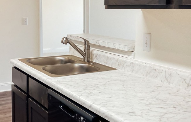 a kitchen with marble counter tops and a stainless steel sink