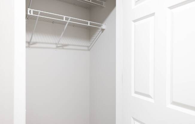 a walk in closet with a white door and a white wall with a hanging rack