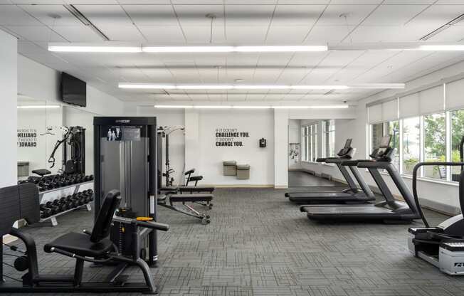 a gym with treadmills and other exercise equipment in a large room with windows